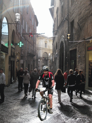 Don Brunetto fa le prove con la bicicletta in centro...